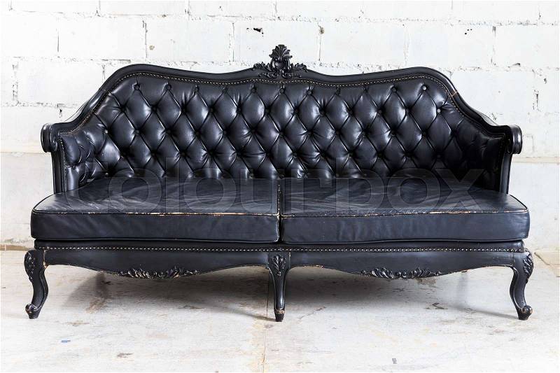 Black vintage sofa on white wall, stock photo