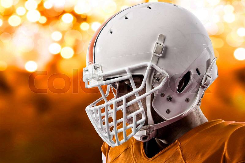 Close up of a Football Player with a orange uniform on a orange lights background, stock photo