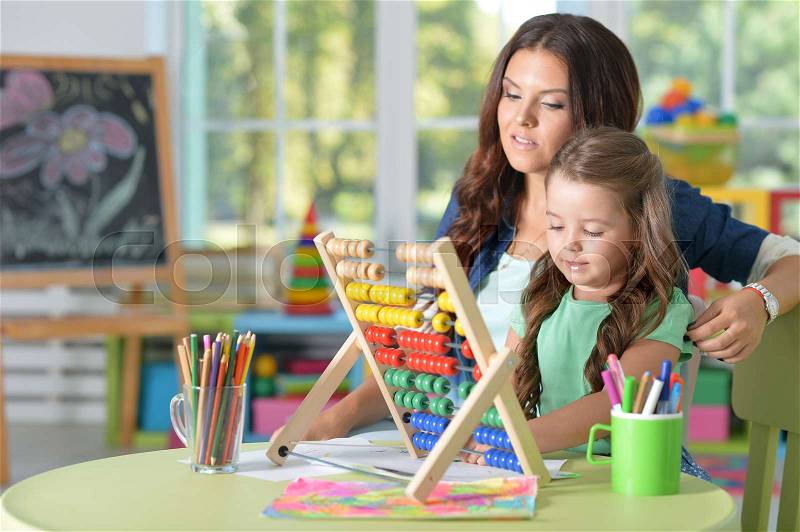 Portrait of a girl doing math exercises with mother, stock photo