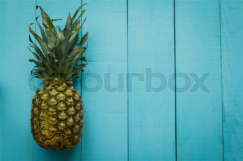 Green pineapple on a blue wooden table, stock photo