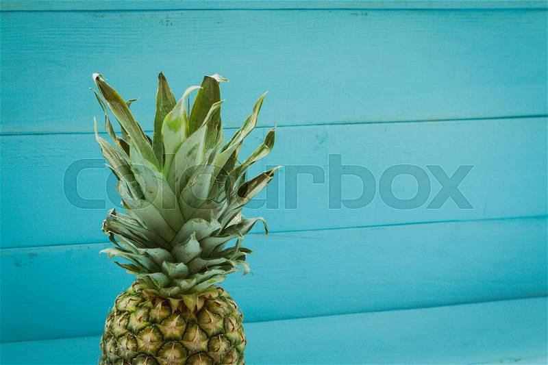 Green pineapple on a blue wooden table, stock photo