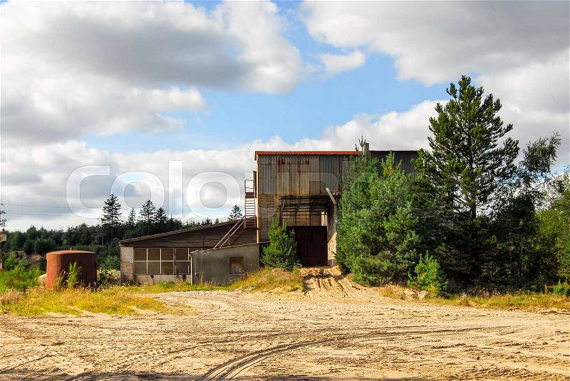 Old abandoned defaulted industrial building which stands with rusty and empty silo, stock photo