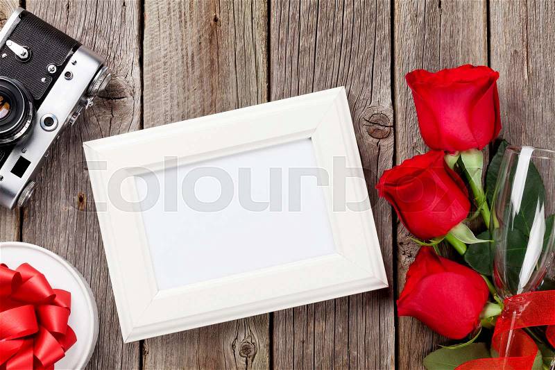 Valentines day roses, photo frame, retro camera and gift box over wooden background, stock photo