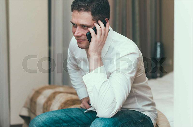 Man with mobile phone in hotel room, stock photo