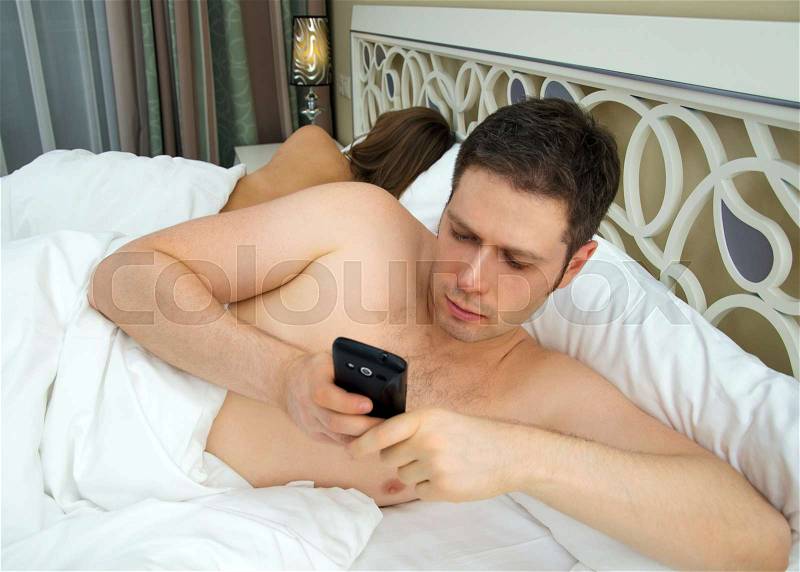 Man cheating while wife is sleeping, stock photo