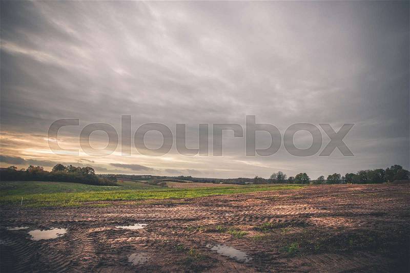 Landscape with wheel tracks on a muddy field in autumn in cloudy weather in off-road terrain, stock photo