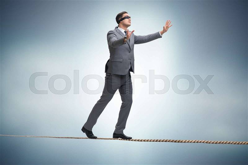 Man walking in tight rope blindfold, stock photo