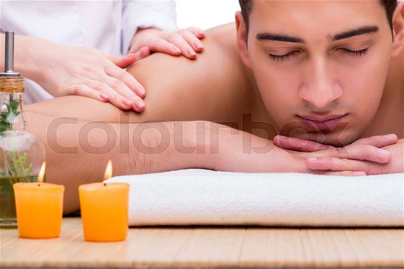 Handsome man during spa massaging session, stock photo