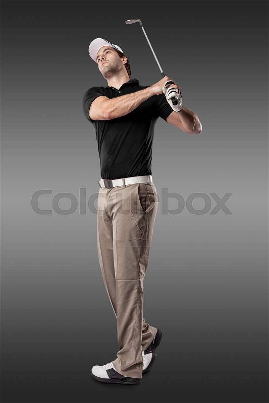 Golf Player in a black shirt taking a swing, on a black Background, stock photo