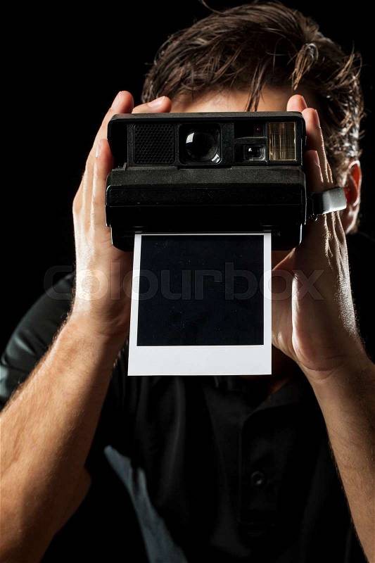 Photographer with a instant camera with a photography on black, stock photo
