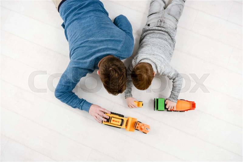 Top view of father dressed in blue sweater playing toys with his little cute son, stock photo