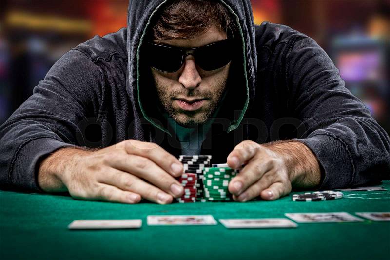 Poker player taking poker chips after winning, , on a cassino background, stock photo