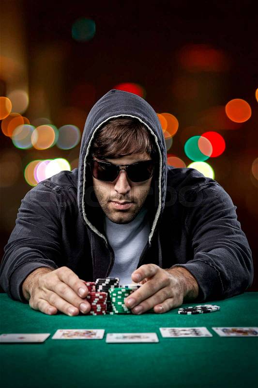 Poker player taking poker chips after winning, , on a bokeh lights background, stock photo