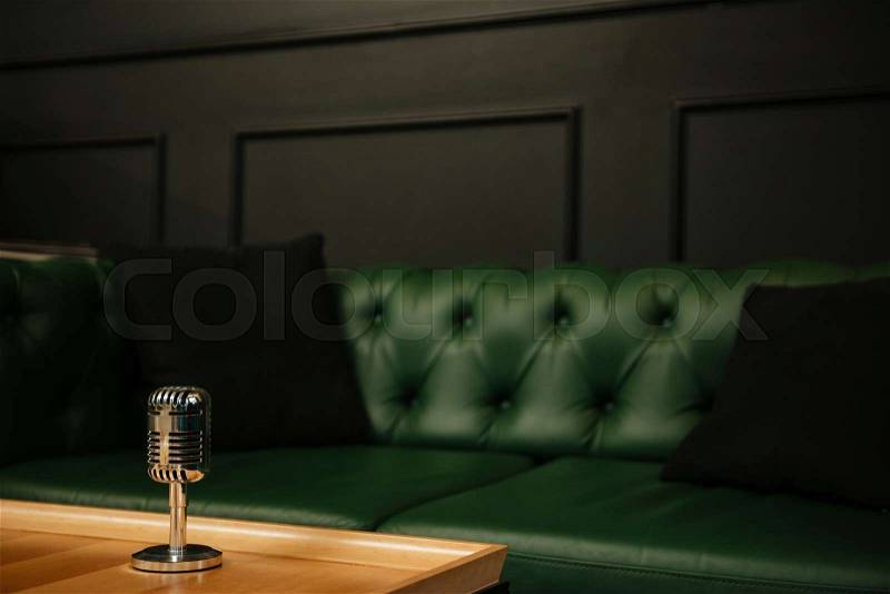 Picture of retro microphone against restaurant background with sofa, stock photo