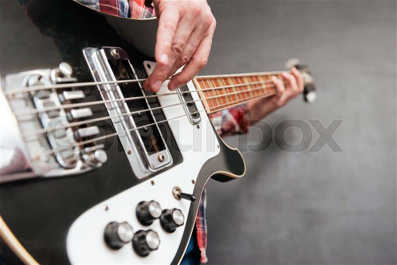 Closeup of man hands holding and playing guitar over grey background, stock photo