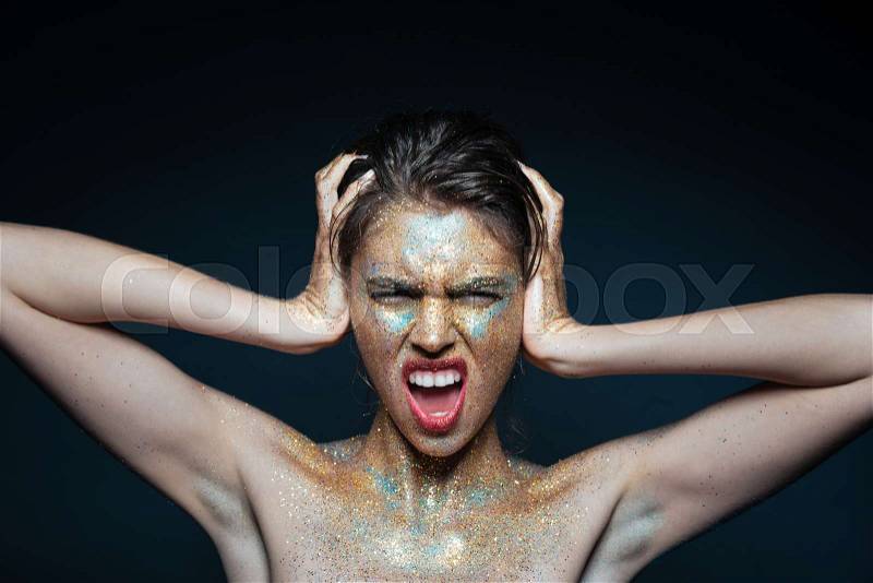 Mad young woman with shimmering makeup standing and shouting, stock photo