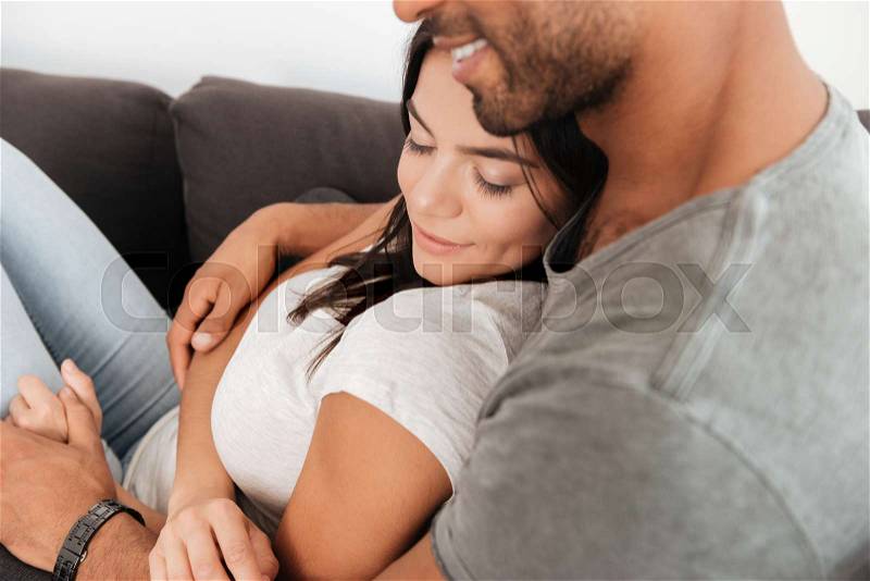 Cute loving couple lies on a sofa at home while hugging. Woman sleeping, stock photo
