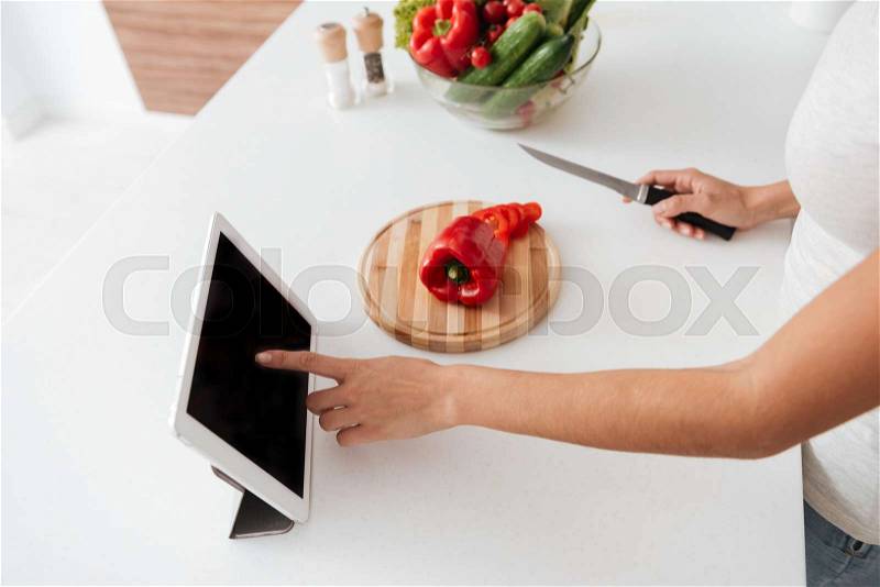 Cropped picture of young woman reading recipe from tablet computer, stock photo