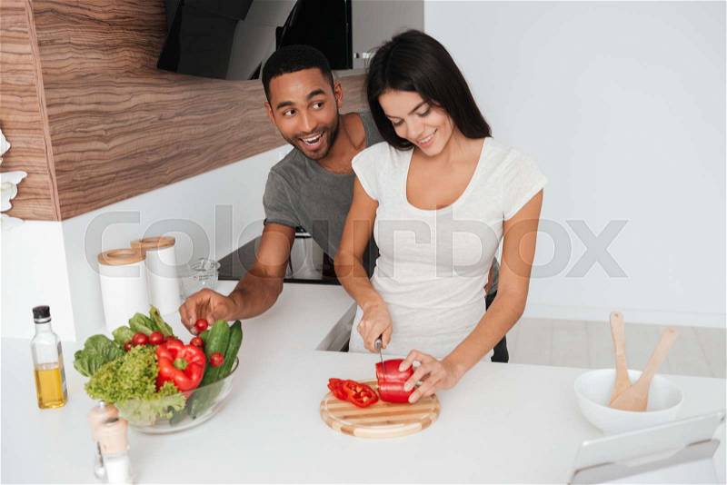 Picture of funny loving couple in the kitchen cooking. Man takes away the products, stock photo