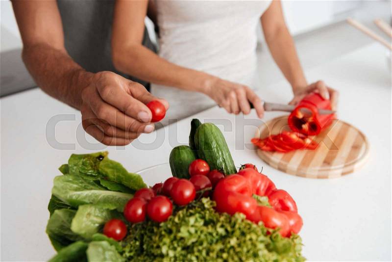 Cropped image of loving couple in the kitchen cooking. Man takes away the products, stock photo