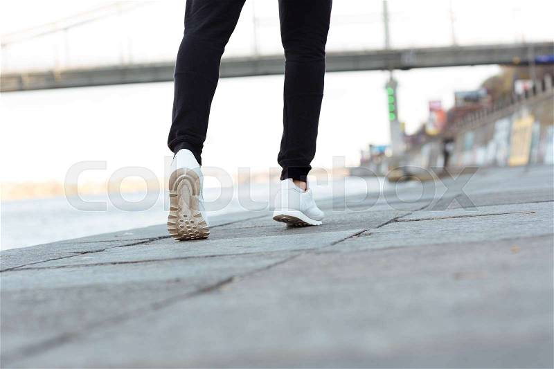 Back view of man athlete legs running outdoors near the river, stock photo