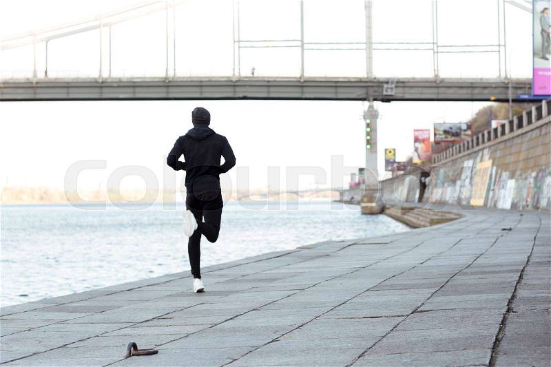 Back view of man athlete running outdoors in autumn, stock photo