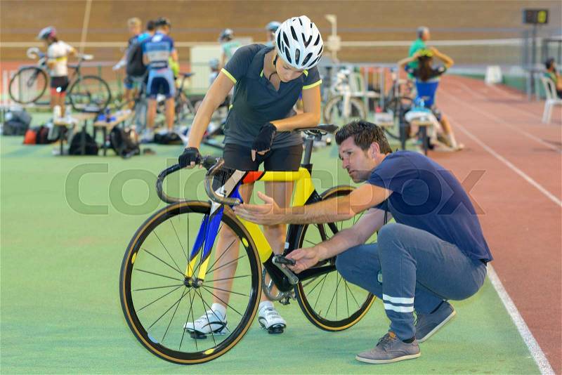 Cyclist and instructor looking at bicycle, stock photo