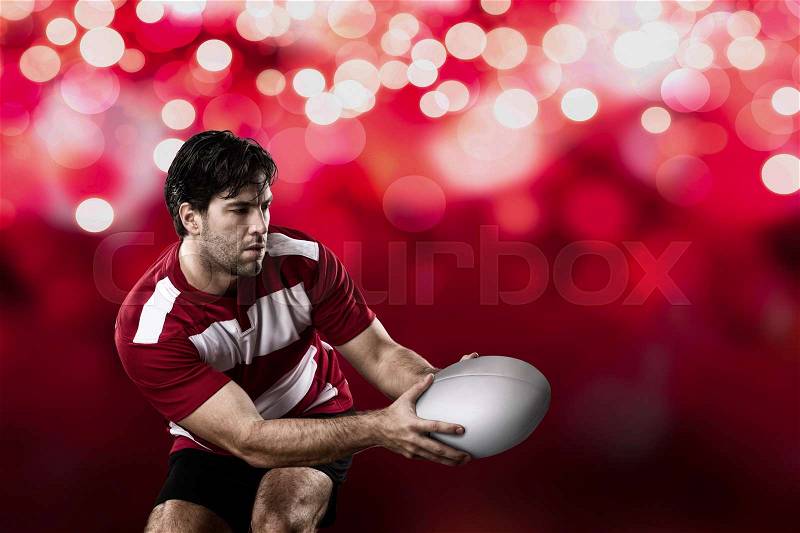 Rugby player in a red uniform on a red lights background, stock photo