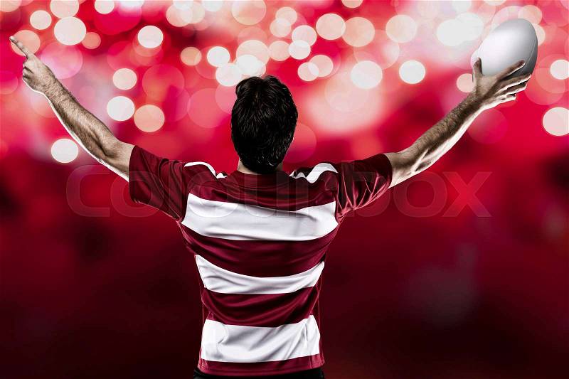Rugby player in a red uniform celebrating on a red lights background, stock photo