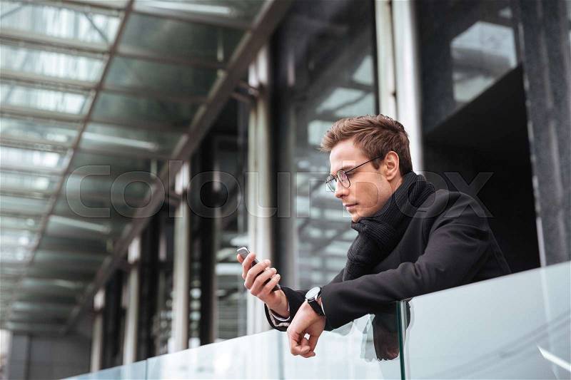 Business man in glasses with phone near the office. side view, stock photo
