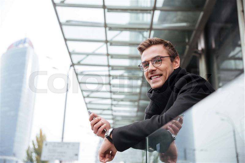 Business man near the office looking at camera. man in glasses with phone, stock photo