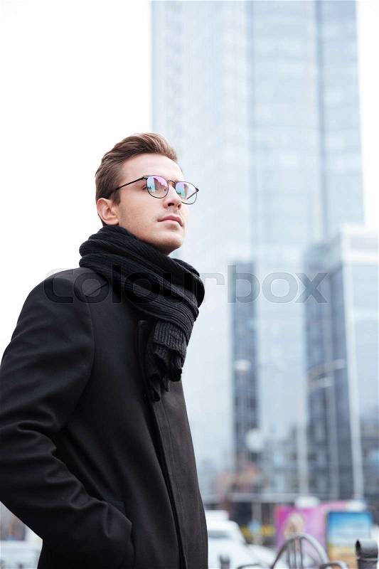 Vertical image of business man in glasses on the street. stands sideways, stock photo