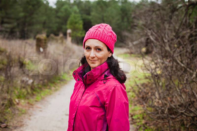 Matured woman with wool pink hat in the forest, stock photo