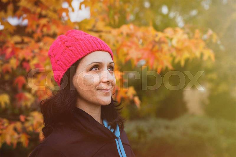 Matured woman with pink wool hat in the forest, stock photo