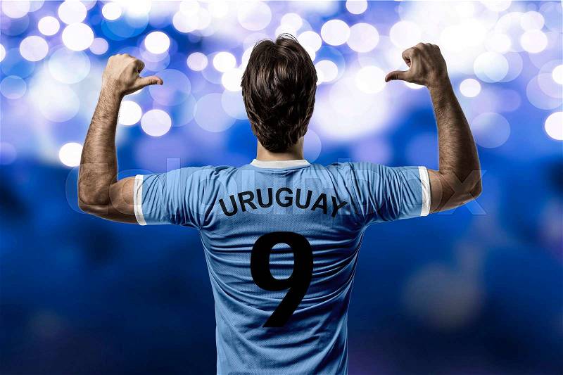 Uruguayan soccer player, celebrating on a blue lights background, stock photo