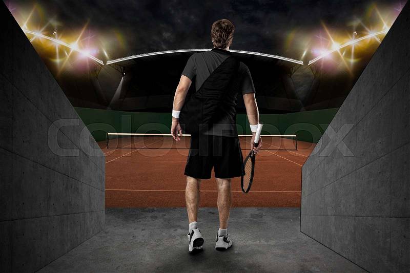 Tennis player with a black shirt, entering a clay tennis court, stock photo