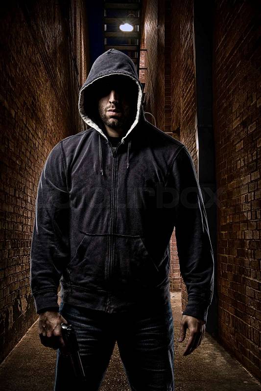 Thief in the hood on a dark alley, stock photo