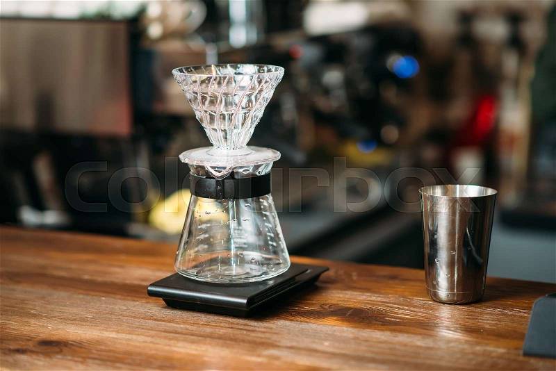 Coffee pot and metal glass on a bar counter. Blury coffee house on background, stock photo