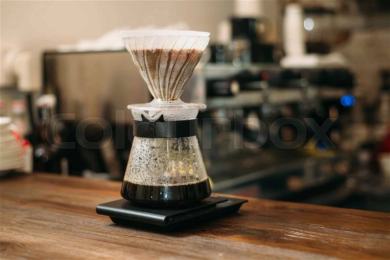 Cooking coffee in a glass pot on bar counter. Blury coffee house on background, stock photo