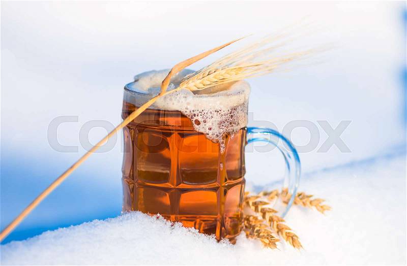 Light beer in the snow with ears of wheat. winter background, stock photo