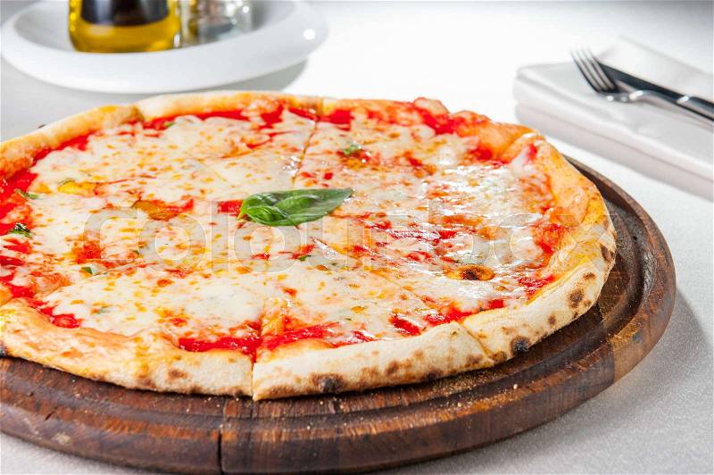 Selective focus traditional stone-baked pizza Margarita on served restaurant table, stock photo