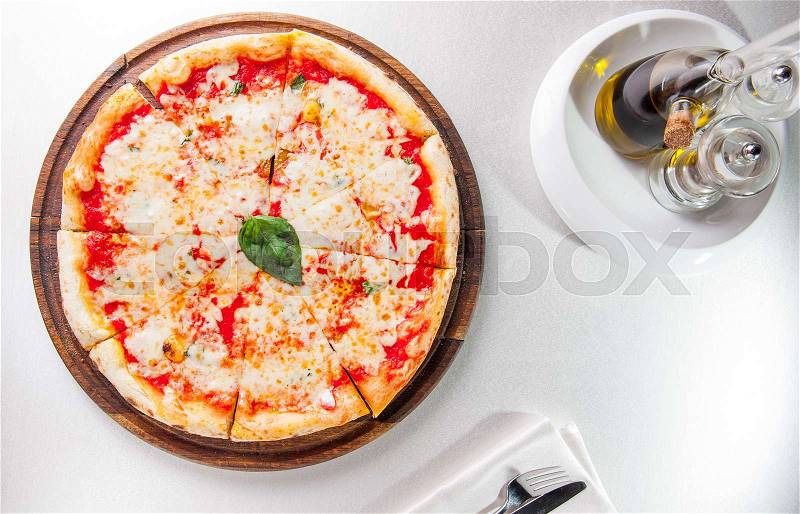 Selective focus traditional stone-baked pizza Margarita on served restaurant table. Top view, stock photo