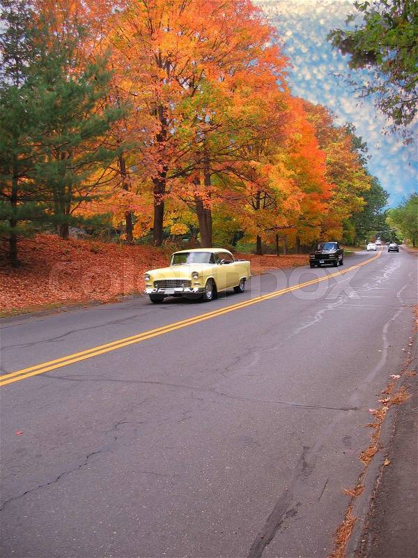 A vintage american muscle car driving down the road on a nice autumn day, stock photo