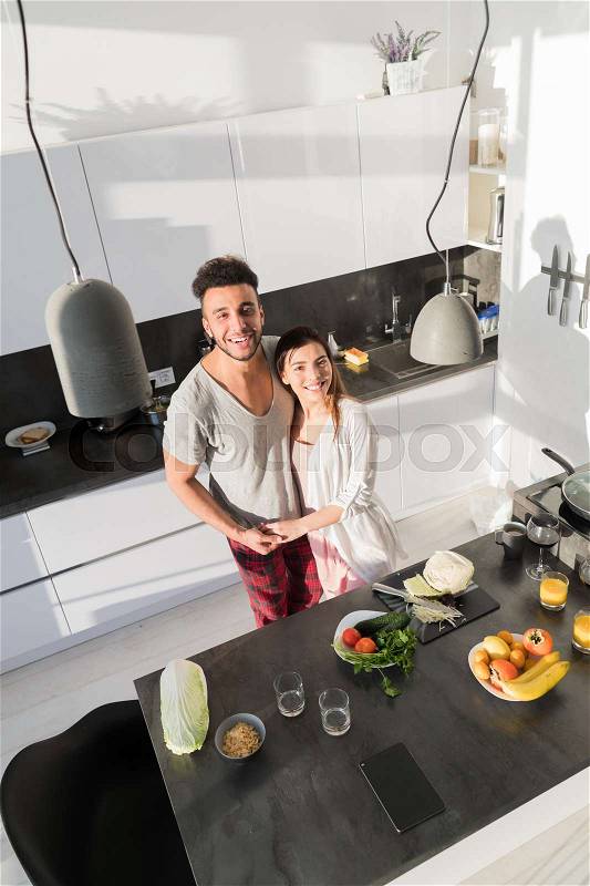 Young Couple Embrace In Kitchen, Hispanic Man And Asian Woman Hug Top Angle View Modern Apartment Interior, stock photo