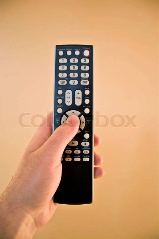 A hand holding a remote control isolated over a gold background, stock photo