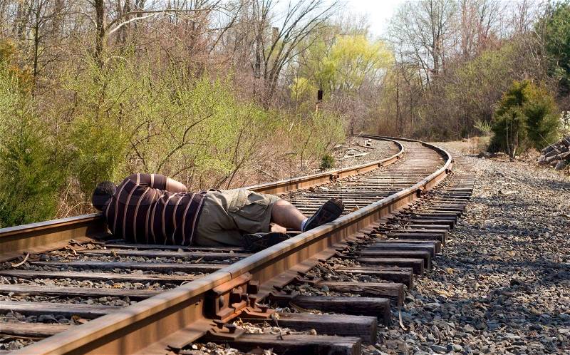 A man laying on the railroad tracks Not exactly the smartest thing to do, stock photo