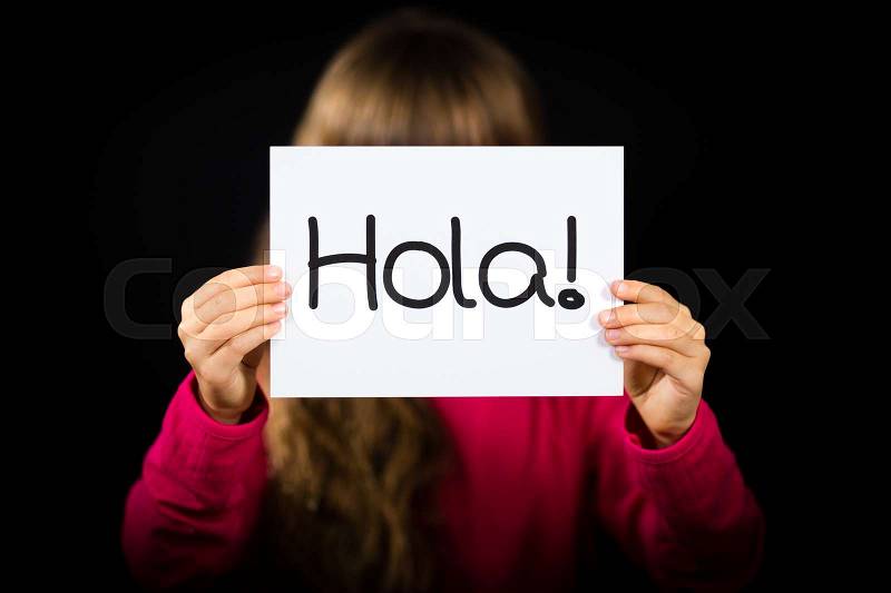 Studio shot of child holding a sign with Spanish word Hola - Hello, stock photo