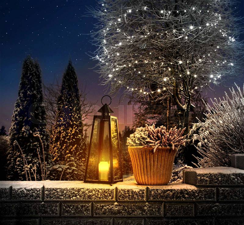 Christmas lantern on snowy stone wall in winter garden, stock photo