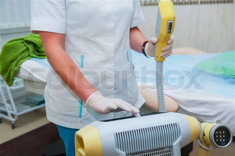 Beautician adjusts laser equipment for cosmetic procedures in cosmeticians office, close up, stock photo