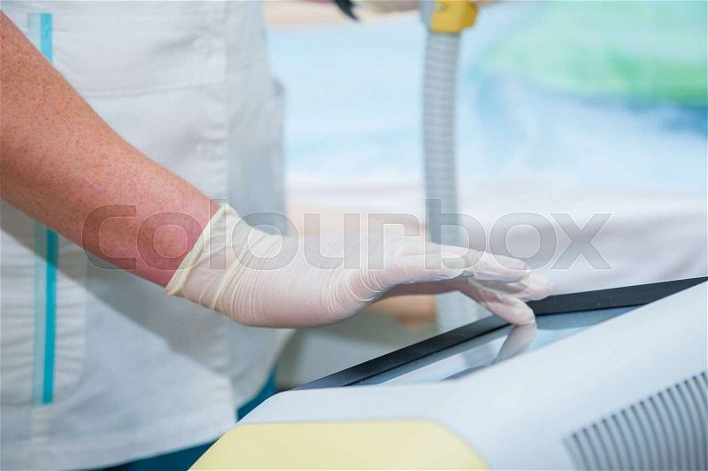 Beautician adjusts laser equipment for cosmetic procedures in cosmeticians office, close up, stock photo